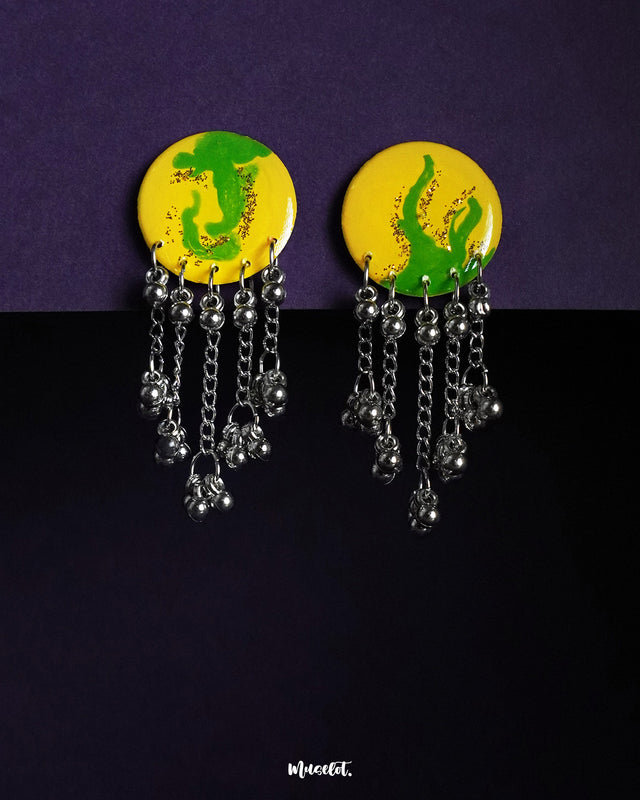The Zarangi drop chain earrings feature a bold yellow and green hand-painted circular top, with cascading silver-toned chains and ghungroo beads, highlighting the vibrant fusion of color and movement while showcasing handcrafted artistry — Muselot.