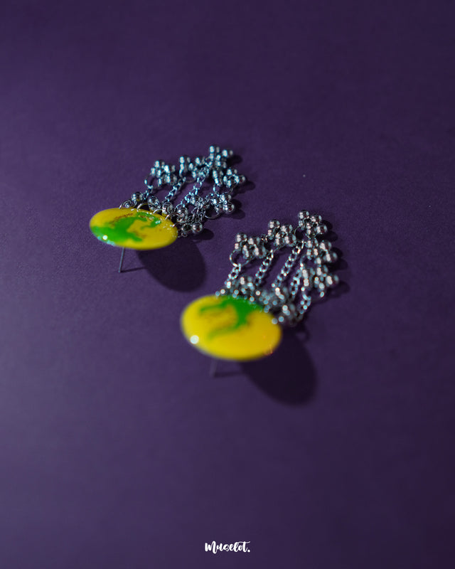 Close-up of Zarangi yellow drop earrings featuring circular tops with green brushstroke-style floral patterns, finished with cascading silver chains and metallic beads for a playful, ethnic charm — Muselot.
