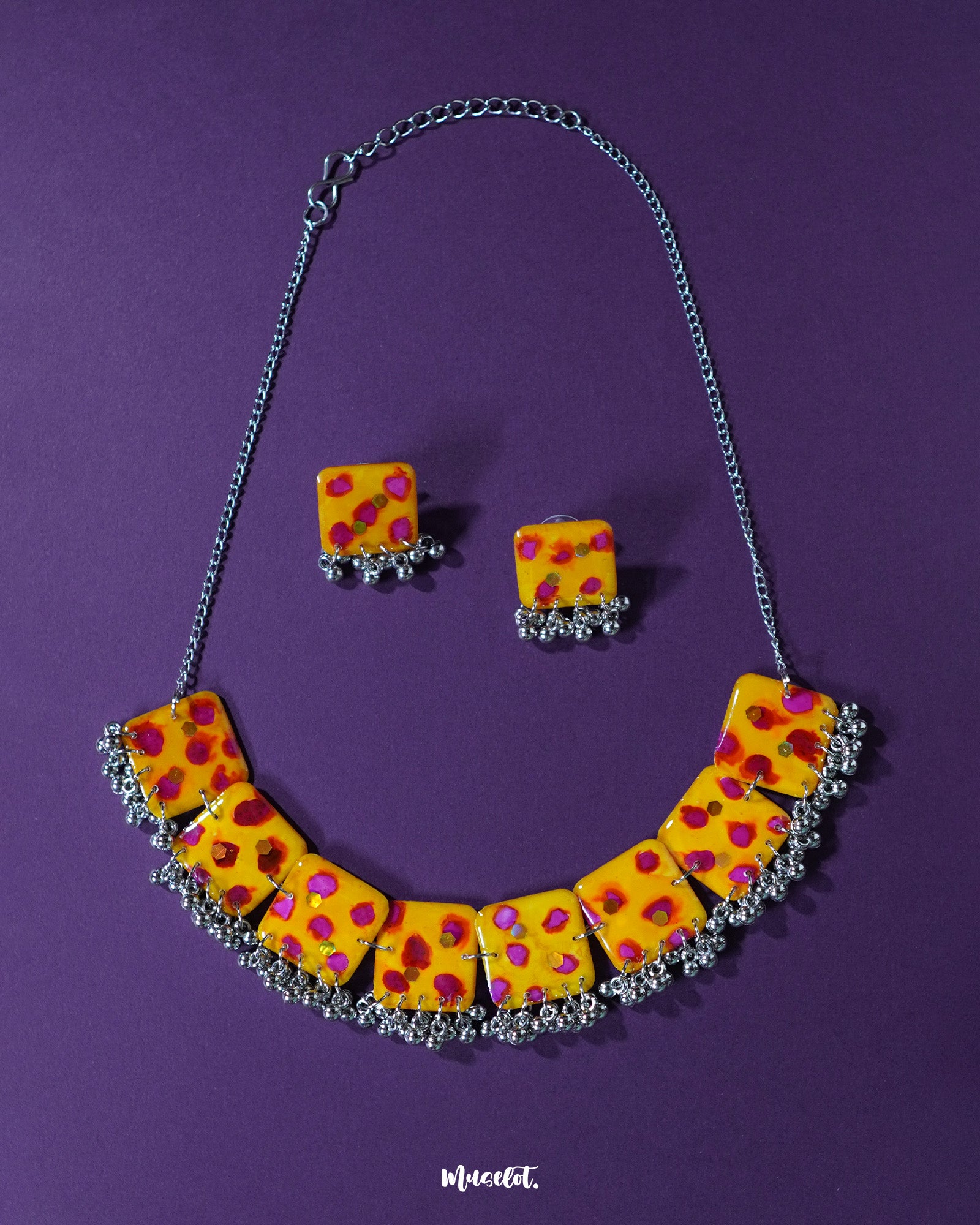 Zard Bahaar handcrafted necklace set with matching earrings, featuring yellow hand-painted square tiles with pink-red floral accents and silver ghungroo detailing, displayed on a purple background – Muselot.