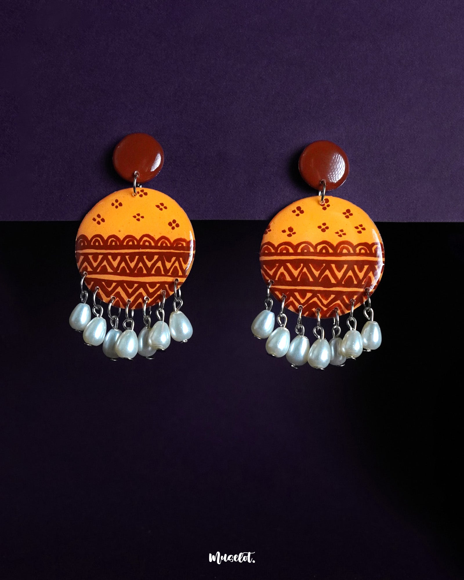 Zardozi drop earrings featuring a bold circular design in warm mustard and rust tones with traditional hand-painted motifs, finished with elegant white pearl danglers—showcasing rich cultural charm and artisanal craftsmanship — Muselot.