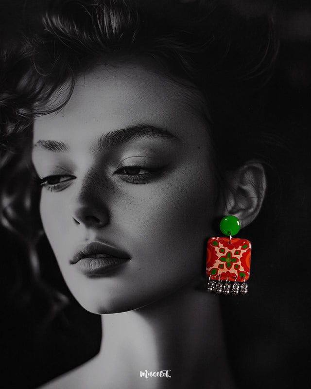 A woman wears the Zarnigar stud earrings, their vivid red and green floral squares adding a bold burst of color near her face. The silver jhumki-style danglers catch the light, creating a playful contrast that enhances her look with handcrafted charm — Muselot.