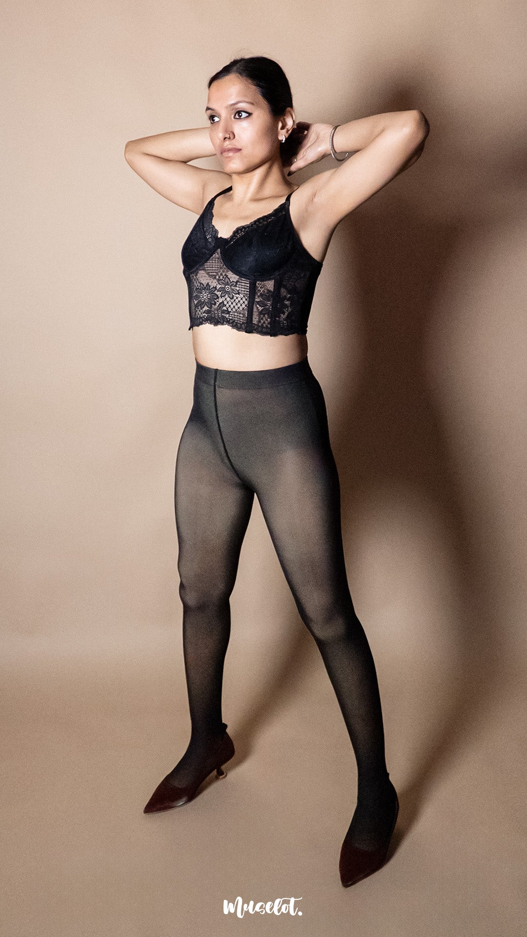 A model wearing black 50 denier stockings side profile on a minimal beige background, showcasing body-hugging fit, stretchable fabric and smooth semi-opaque look — Muselot