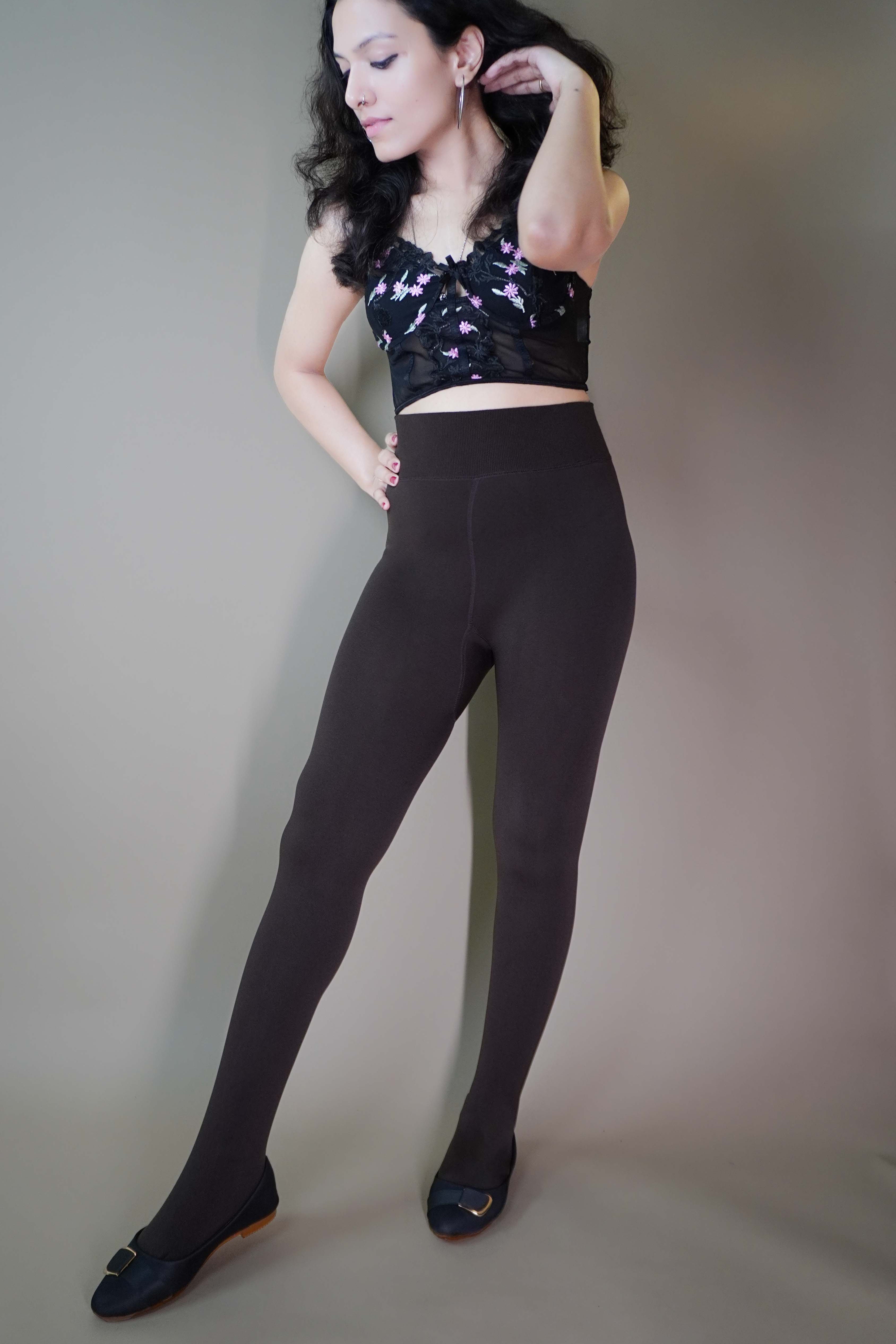 A model, wearing body-hugging brown warm tights, highlighting their snug fit that contours to the body while providing warmth and comfort. The rich brown hue adds depth to the outfit, making these tights both a stylish and cozy option for cooler weather. -Muselot