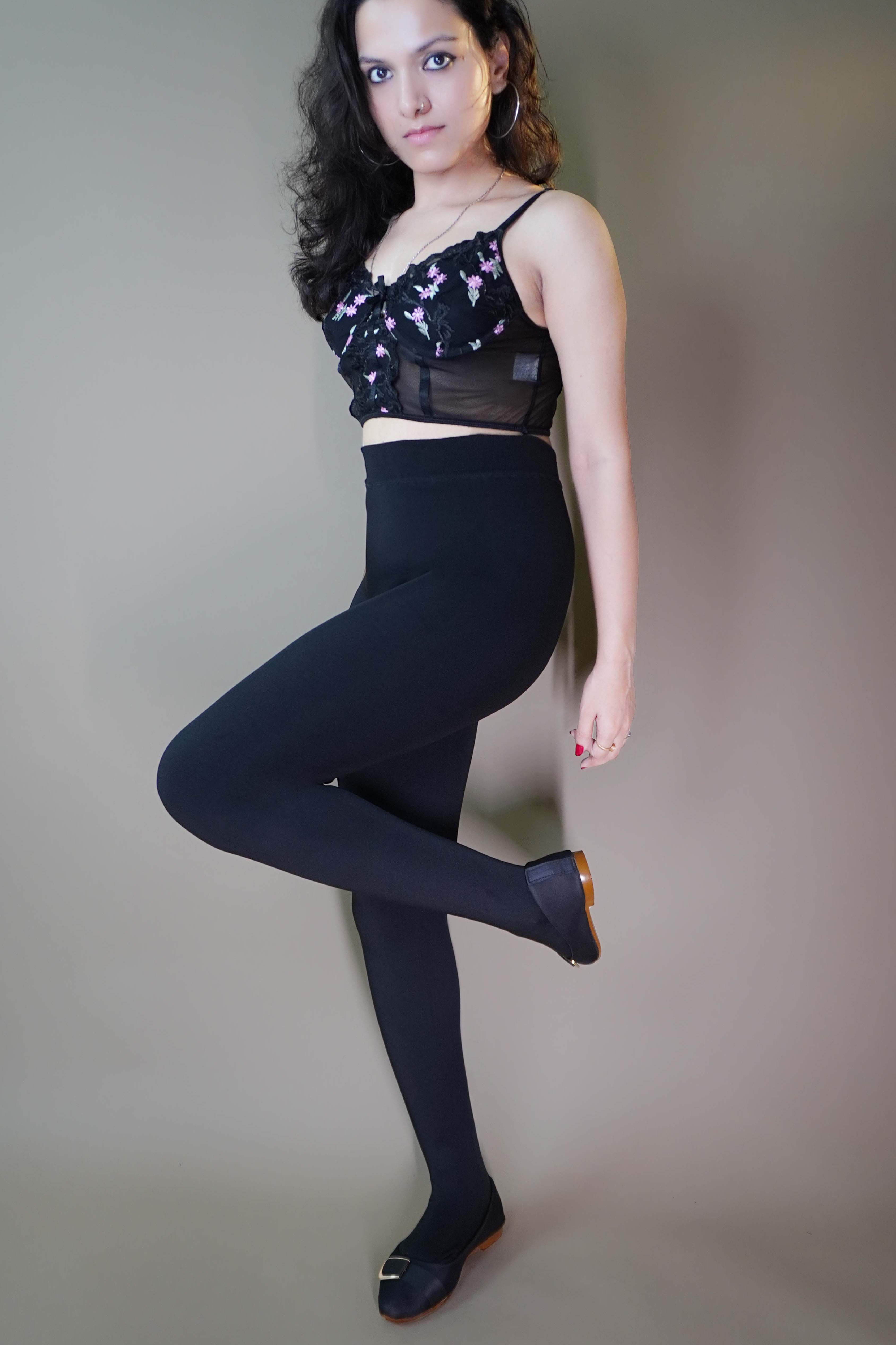 A stylish model wearing a body-hugging black warm tights, offering a sleek, form-fitting silhouette while providing comfort and warmth. The tights perfectly complement the model's figure, making them a stylish and cozy choice for any occasion. -Muselot