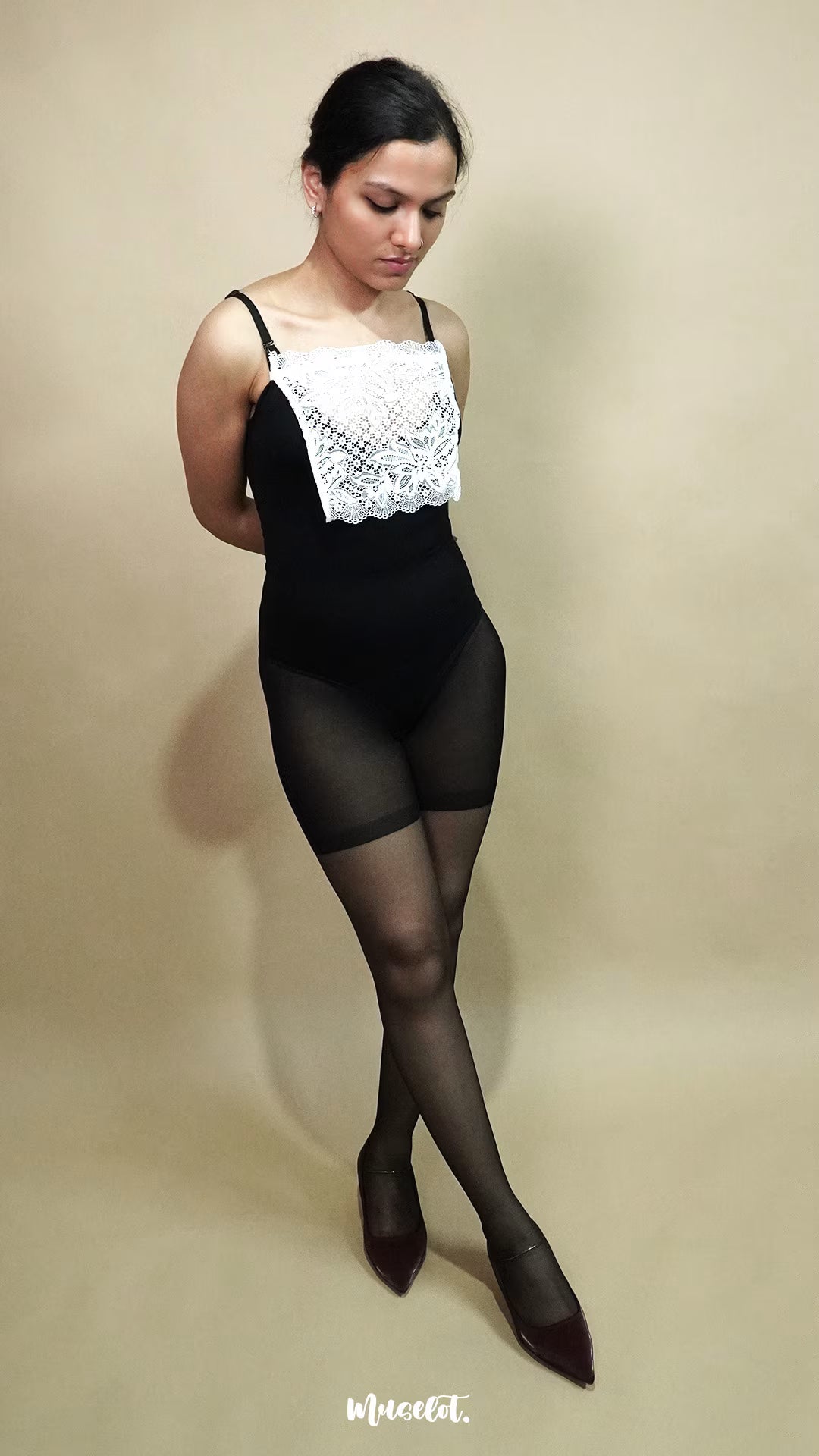 full length pose of woman wearing white lace camisole insert over black bodysuit on beige background, showing how mock lace panel adds neat coverage to deep neckline – muselot