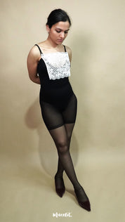 full length pose of woman wearing white lace camisole insert over black bodysuit on beige background, showing how mock lace panel adds neat coverage to deep neckline – muselot
