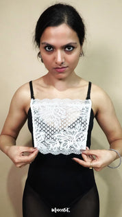 front view of woman holding white lace camisole insert to display full width and shape, showing mock lace layer used for covering deep neck tops neatly – muselot