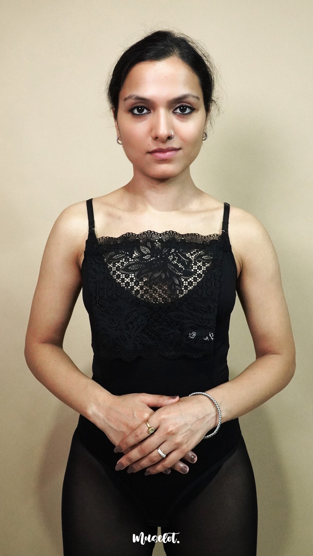 front view of woman holding black lace camisole insert to show size and shape on beige background, highlighting broad lace coverage made for deep neck dresses and tops – muselot