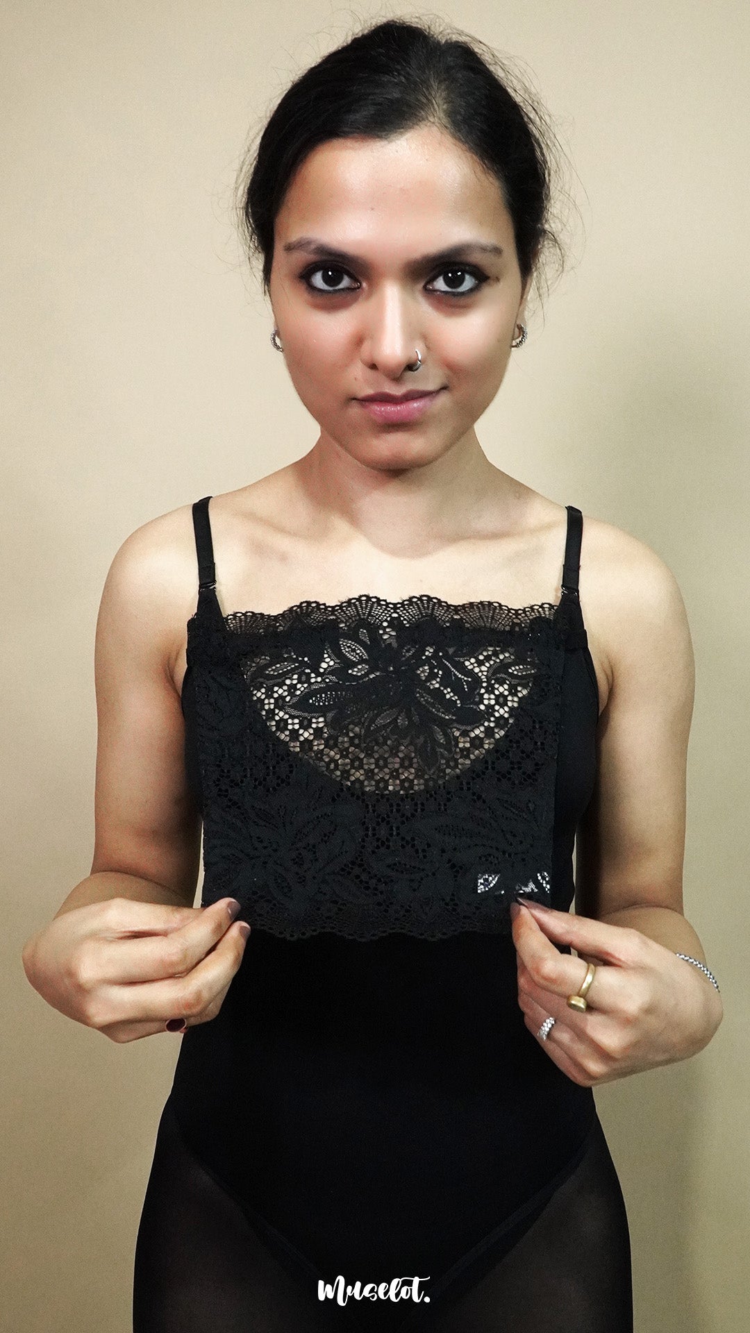 front view of woman holding black lace camisole insert to show size and shape on beige background, highlighting broad lace coverage made for deep neck dresses and tops – muselot