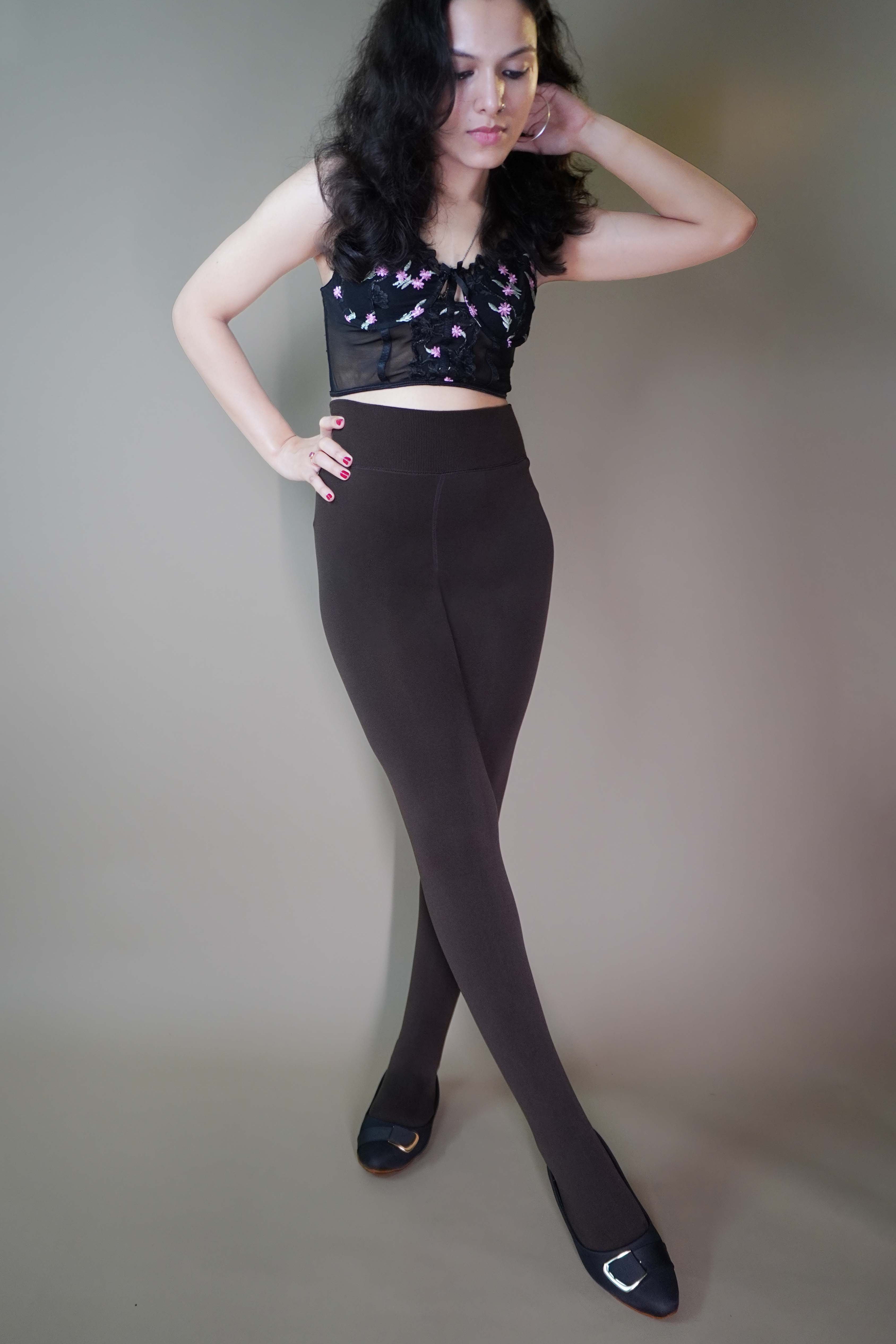 A model, wearing closed-feet dark brown warm stockings, is showcasing their thick, insulating fabric that offers both warmth and comfort. The deep dark brown color highlights a sleek, full-coverage design, making them a stylish and cozy choice for colder days. -Muselot