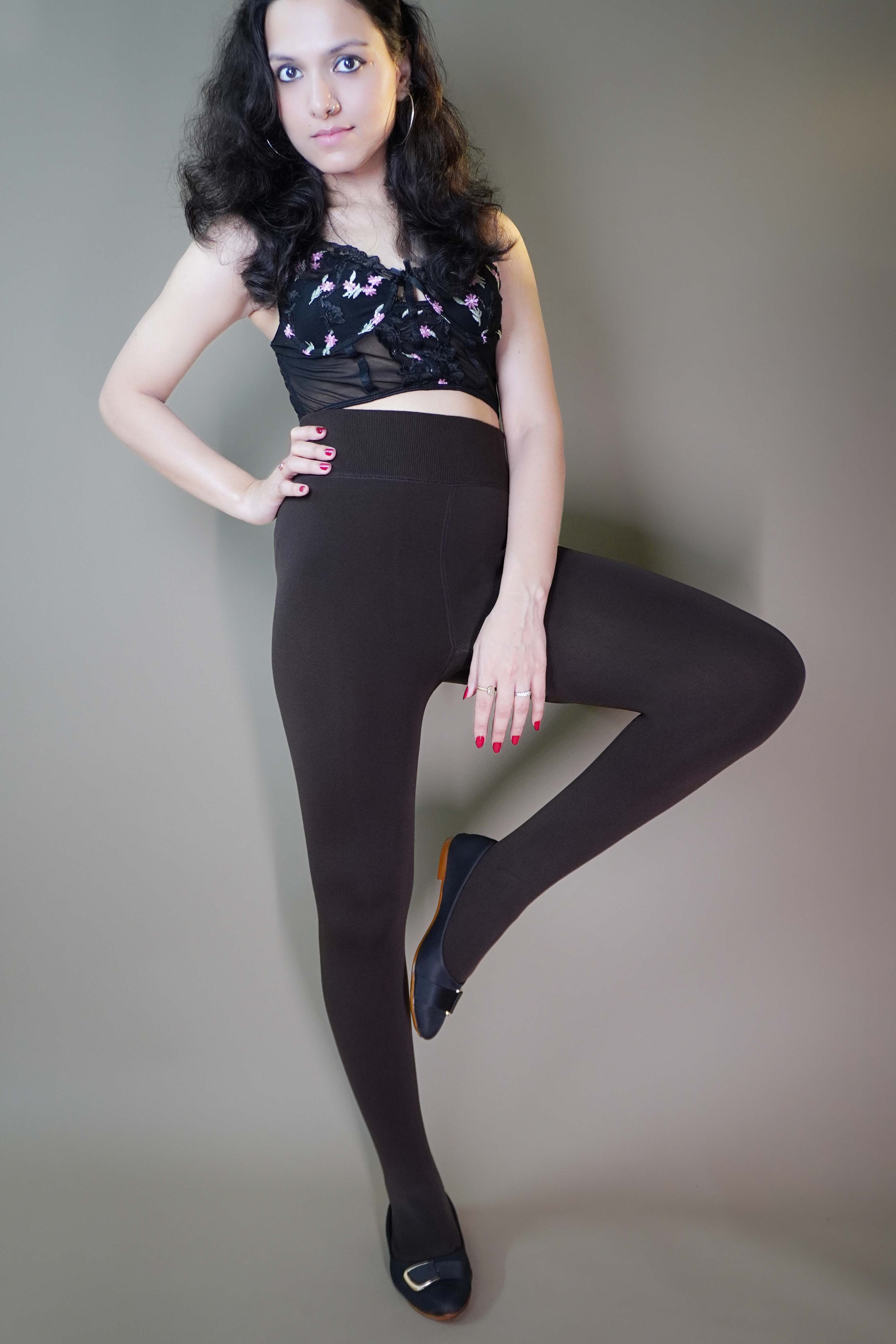 A model, wearing dark brown warm tights, is showcasing their smooth, thick fabric that offers a snug fit and ample warmth. The deep brown hue highlights a classic, versatile look, making these tights a stylish and practical addition to any cold-weather outfit. -Muselot