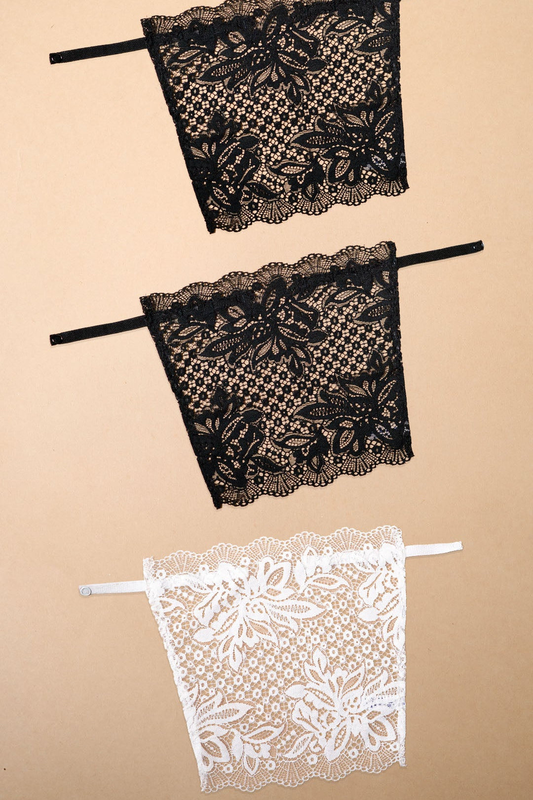 Three lace clip-on neckline covers in black and white displayed on a beige background, featuring floral lace detailing, adjustable straps and elegant coverage for deep neck tops, dresses and blouses, offering a stylish alternative to camisoles and modesty panels – Muselot
