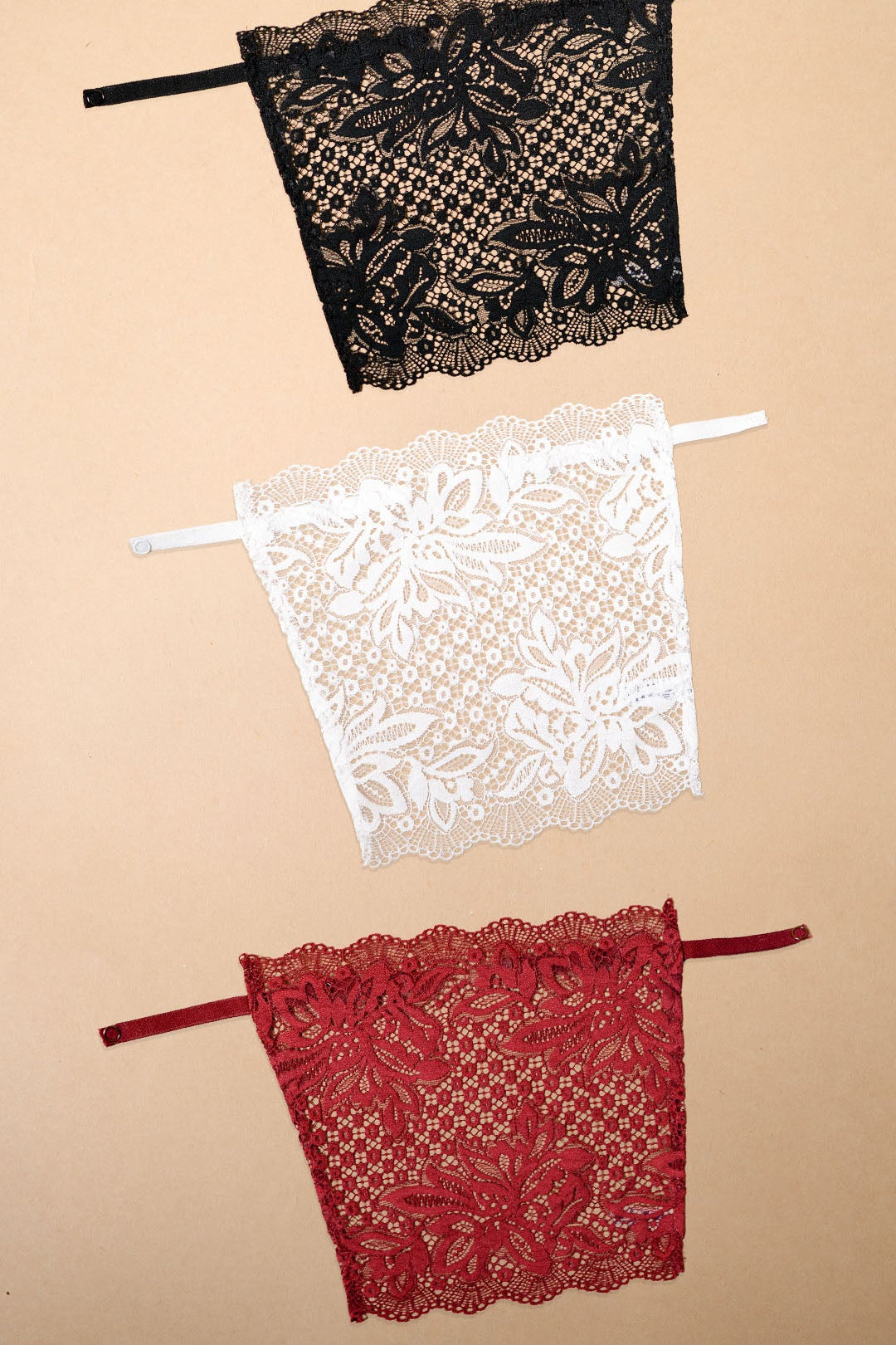 Three floral lace deep neck cover-up camisoles in black, white and maroon arranged on a beige background, showcasing versatile colour options for neckline coverage, layering and styling with dresses, tops and blouses – Muselot