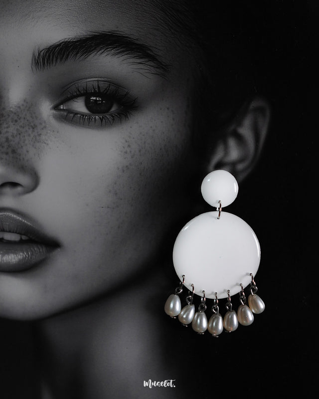 Close-up of a woman wearing designer stud drop earrings, featuring smooth white circular tops with delicate pearl drops, highlighting the graceful fusion of simplicity and elegance — Muselot.