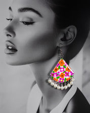 Model wearing floral hook earrings, showcasing vibrant hand-painted multicolour design with white pearl drops, styled to highlight their bold and playful charm – Muselot.