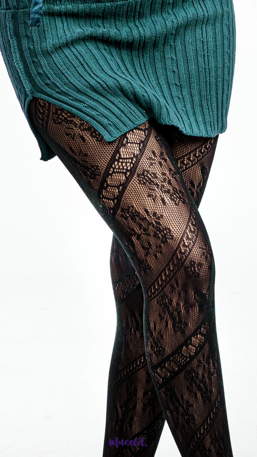 A model wearing black lace stockings with detailed floral fishnet texture on a white background, close up highlighting intricate mesh pattern - Muselot