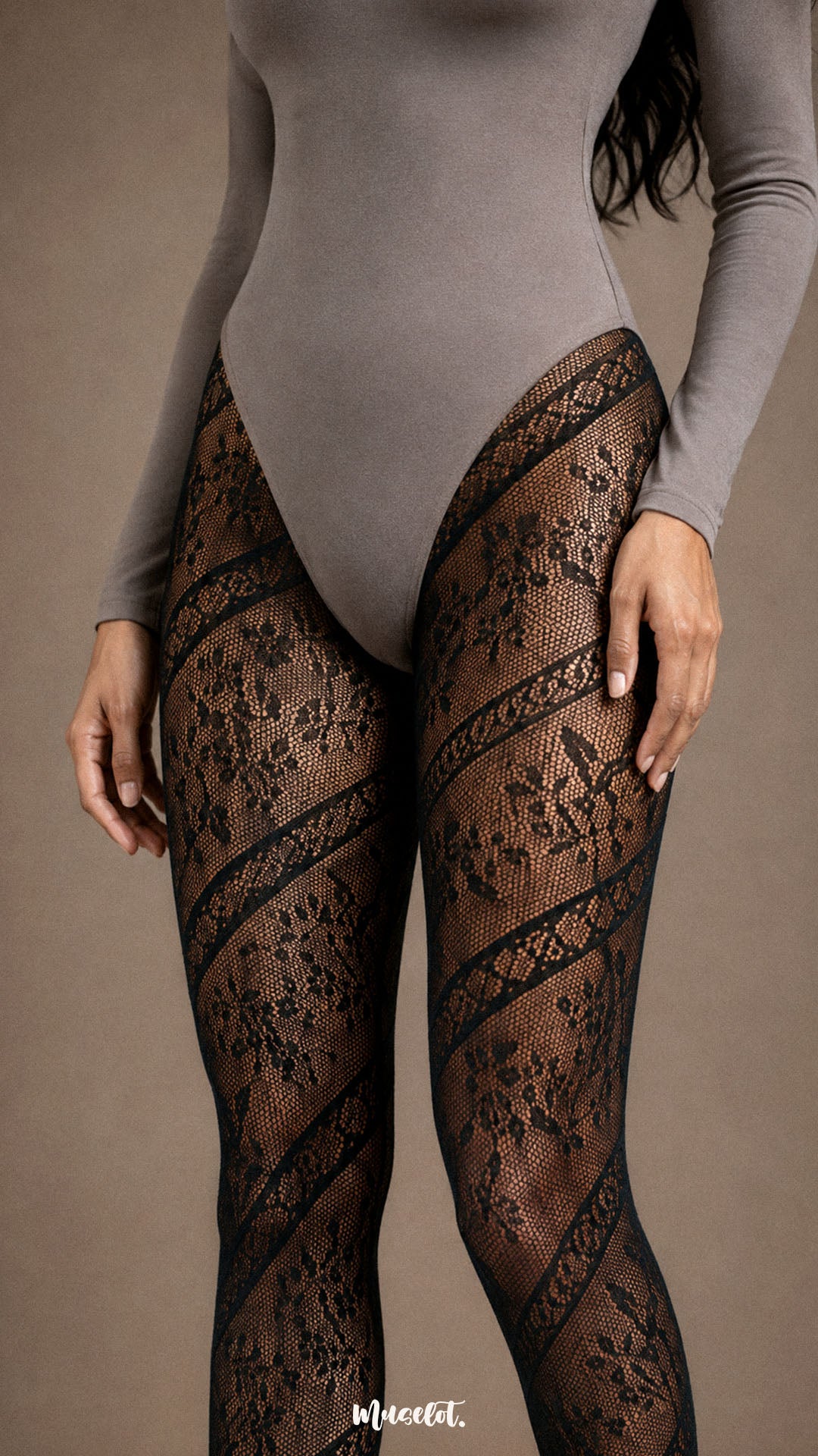 Close-up of black designer lace stockings featuring diagonal floral lace bands and semi-sheer mesh detailing across the thighs - Muselot