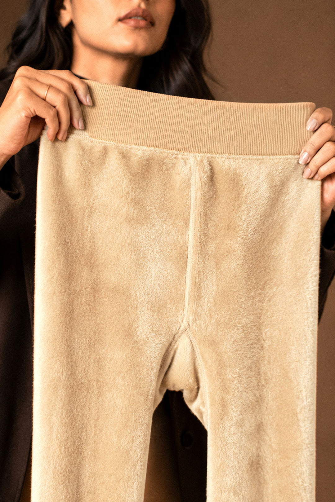A woman holding beige winter stockings open to show the dense soft fleece lining, wide waistband and warm fur interior - Muselot
