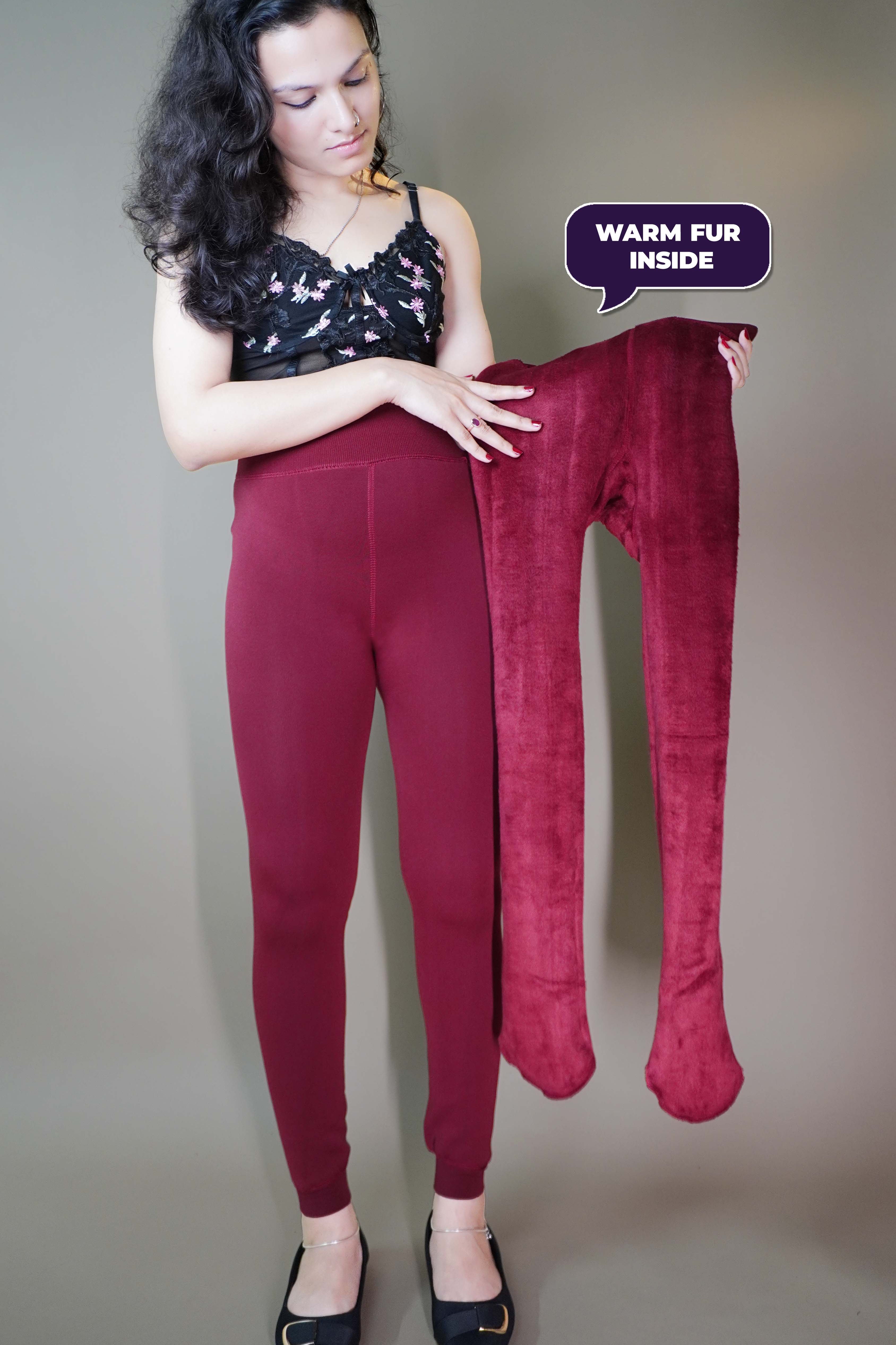 A model, wearing furry berry maroon stockings, and also holding  the tights inside out, showcasing  its plush fur texture. The rich berry color enhances the cozy, luxurious feel, highlighting the softness and warmth of the tights. -Muselot