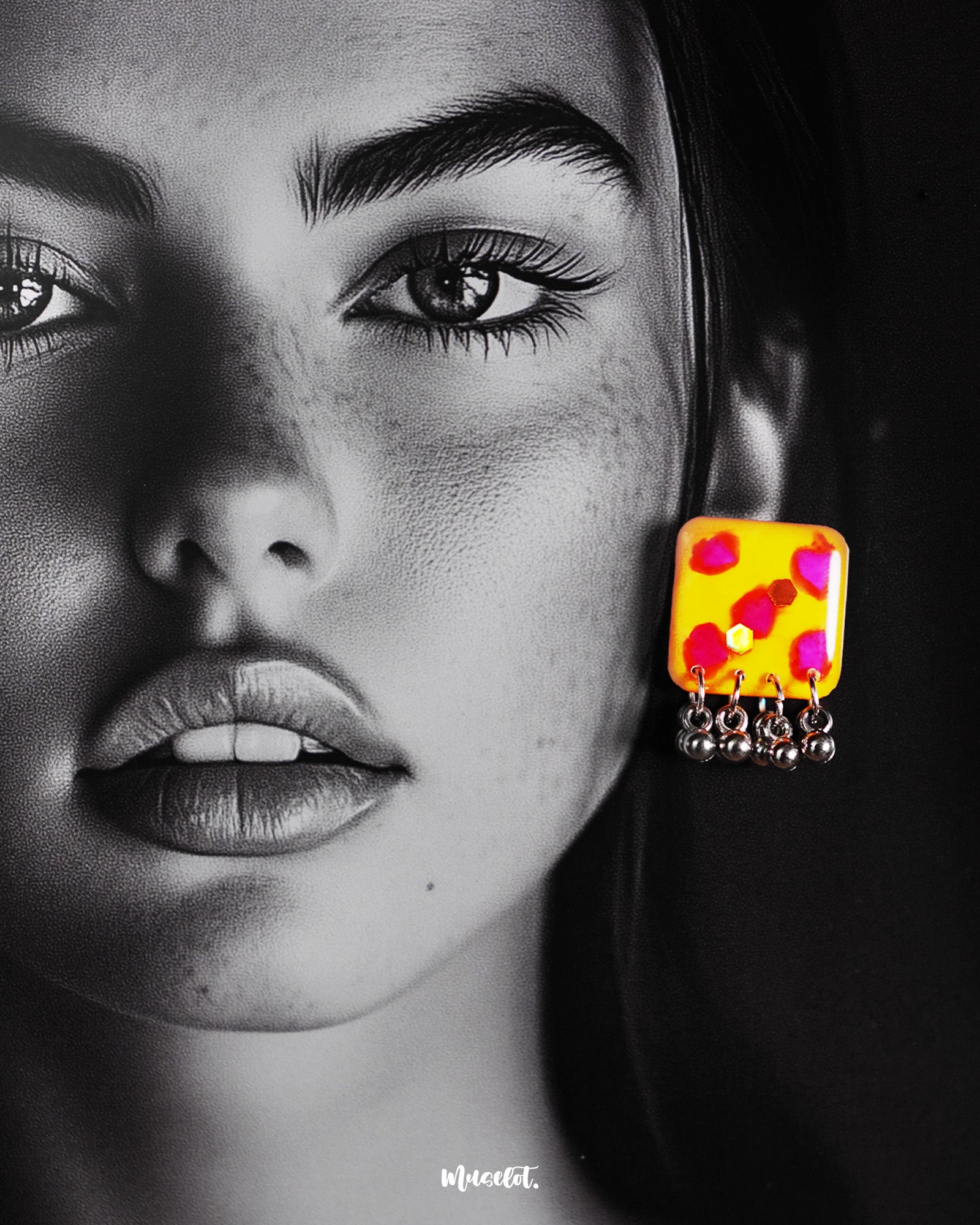Model wearing handmade earrings, highlighting the yellow hand-painted stud with pink-red accents and dangling silver ghungroo detail – Muselot.
