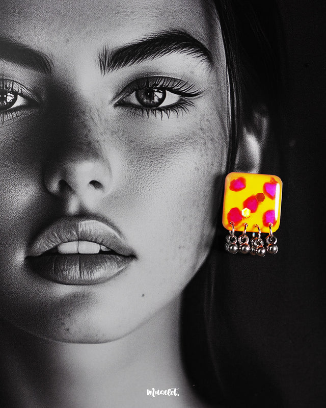 Model wearing handmade earrings, highlighting the yellow hand-painted stud with pink-red accents and dangling silver ghungroo detail – Muselot.