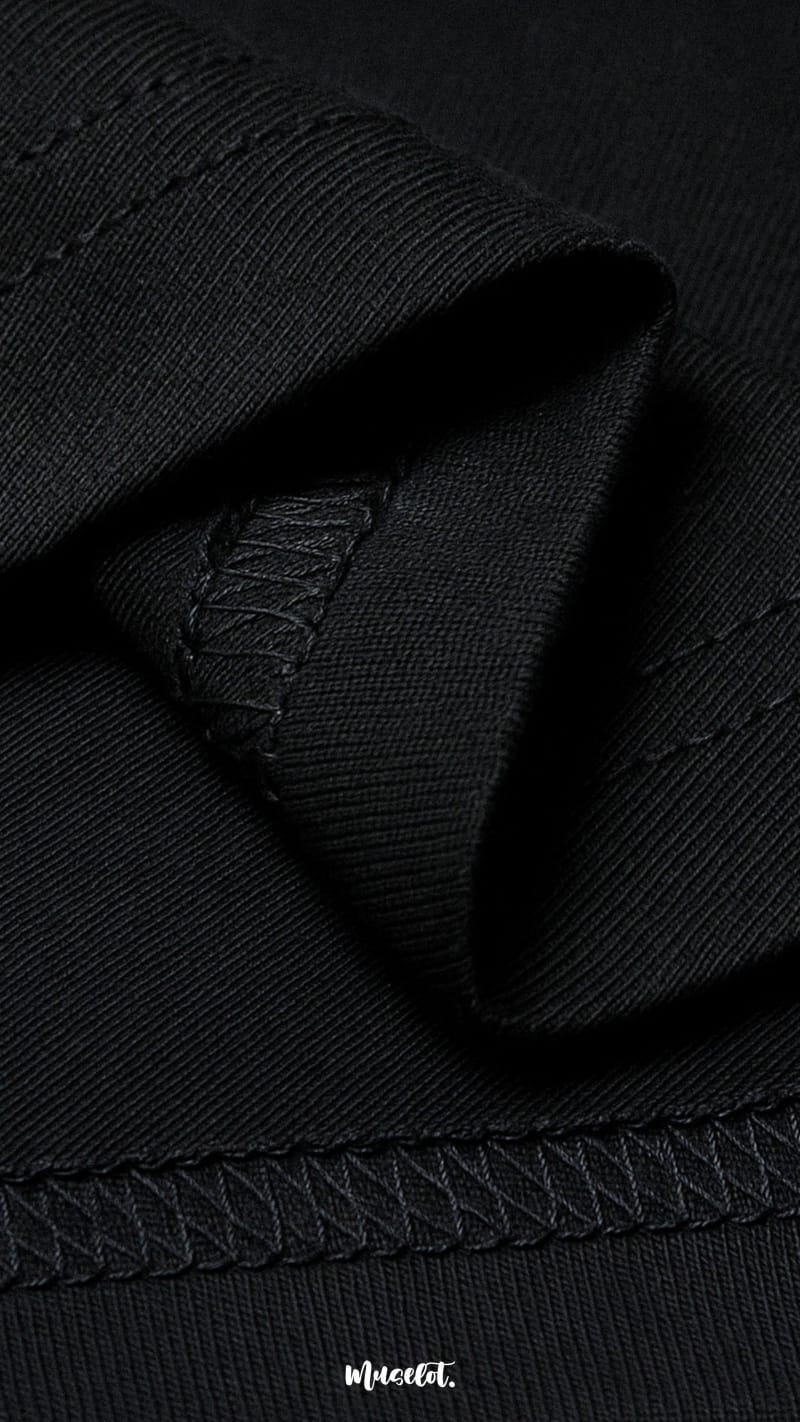 A zoomed-in view of the unisex oversized black t-shirt, highlighting the double seam stitching for added strength, lasting durability, and a neat polished finish—Muselot