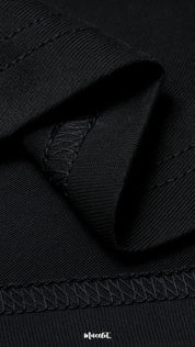 A zoomed-in view of the unisex oversized black t-shirt, highlighting the double seam stitching for added strength, lasting durability, and a neat polished finish—Muselot