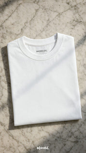 A unisex oversized white T-shirt laid flat in soft sunlight, highlighting its relaxed silhouette and subtle fabric texture, giving off a breezy and versatile vibe — Muselot