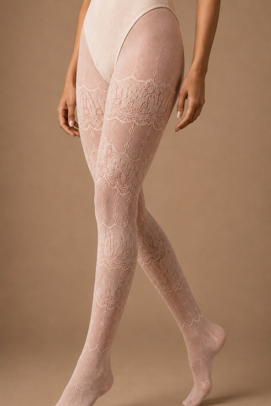 A model wearing pearl pink designer lace stockings from the waist to the feet, showcasing the intricate floral motifs, semi-sheer lace texture and complete full-leg coverage – Muselot.