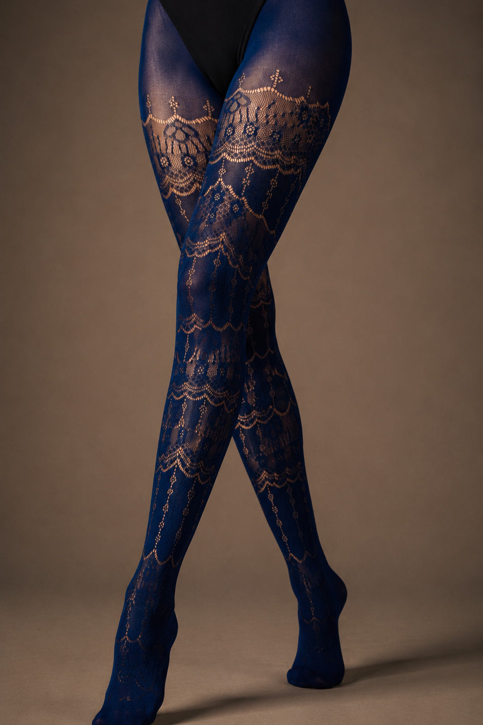 A close-up of crossed legs wearing Sapphire Blue designer stockings with intricate floral lace bands and semi-sheer patterned construction - Muselot