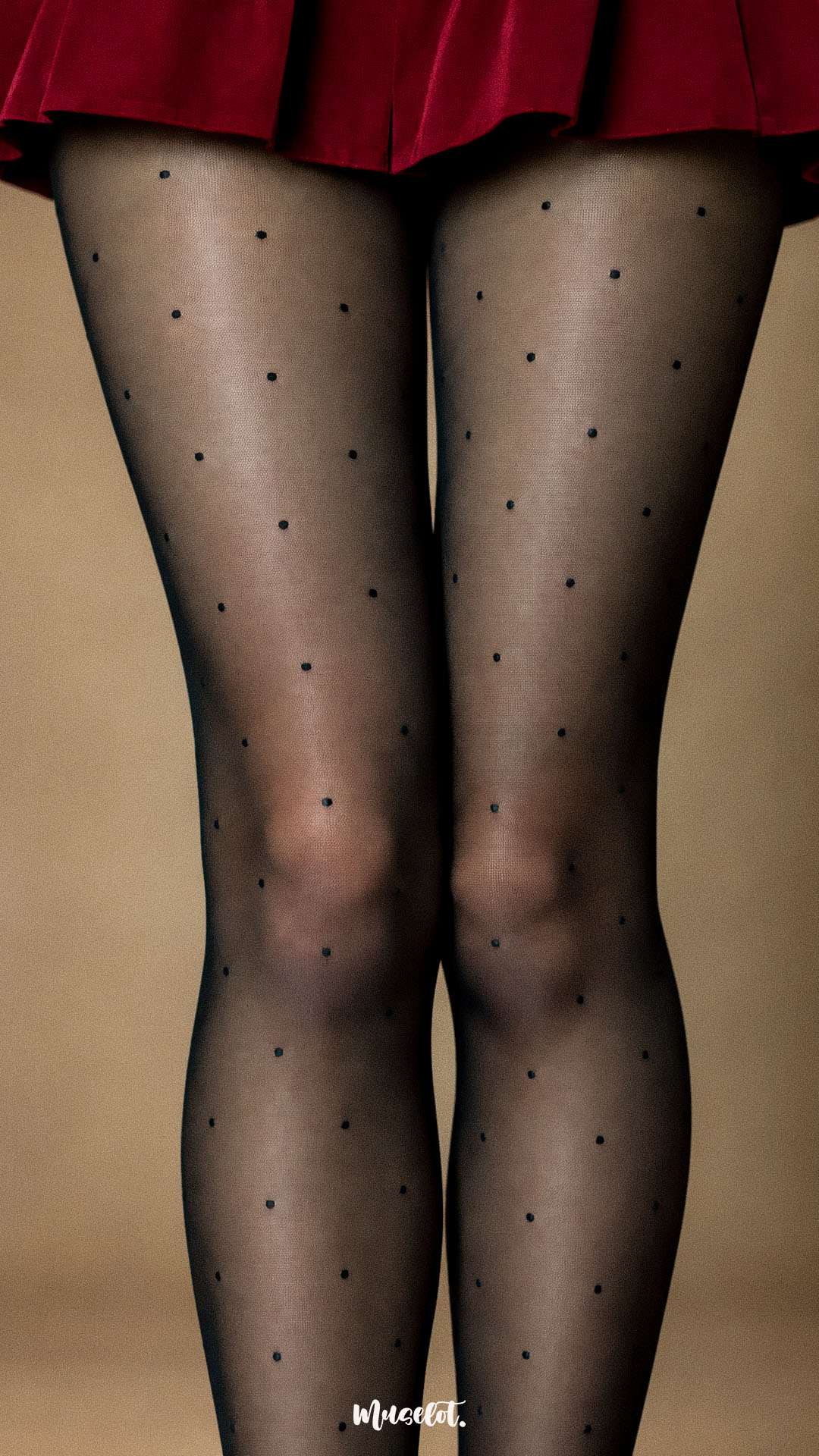 A close-up shot of a woman wearing black sheer-effect polka dot stockings, highlighting the tiny evenly spaced dots, fine mesh-like appearance and smooth finish across both legs - Muselot