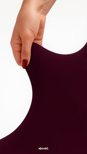 Close-up of hand stretching durable semi-opaque maroon tights, showcasing high elasticity, strength, and tear-proof quality - Muselot