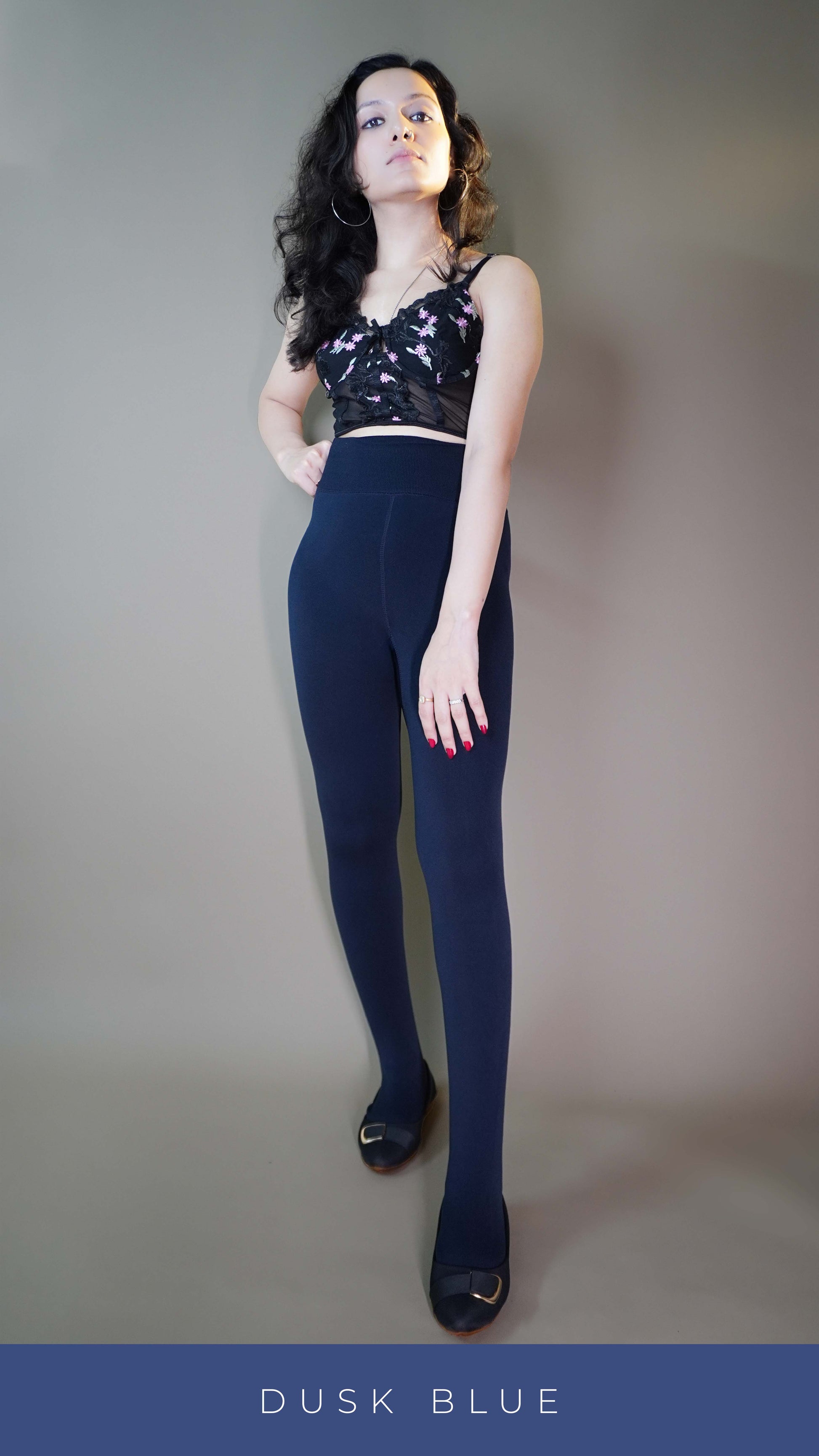 A model wearing fur-lined navy blue tights paired with a stylish floral crop top, highlighting the tights snug fit and luxurious fur lining. The navy blue shade adds elegance, while the outfit accentuates the tights cozy and versatile design—perfect for both style and warmth. -Muselot






