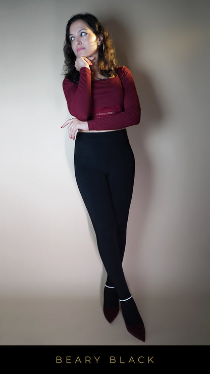 A model, wearing stylish warm velvety black tights, showcasing their soft, luxurious texture that offers both warmth and elegance. The velvety finish and deep black color highlight a chic, sophisticated look, perfect for adding a touch of luxury to any cold-weather outfit. -Muselot