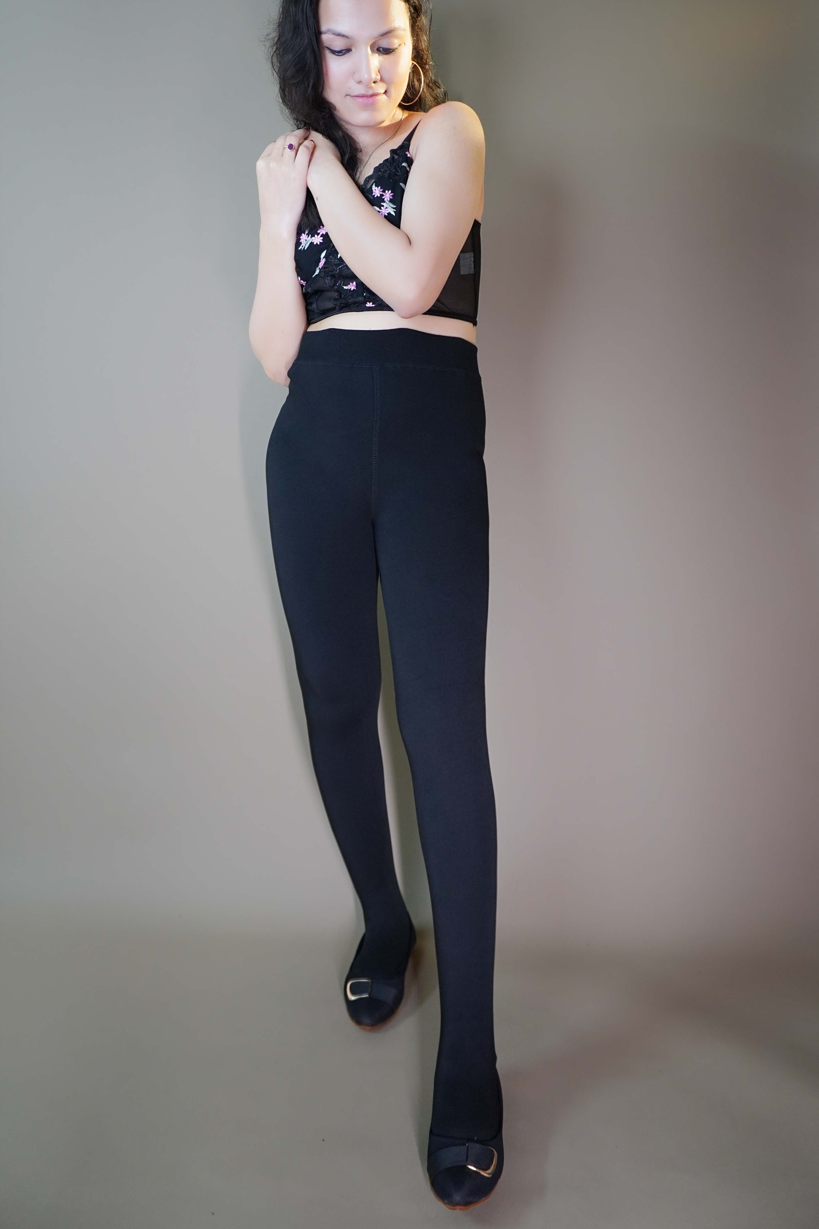 A model, wearing thermal black stockings, showcases their thick, heat-retaining fabric that ensures warmth and comfort. The stockings highlight a smooth, sleek look, providing both practicality and style for colder days. -Muselot