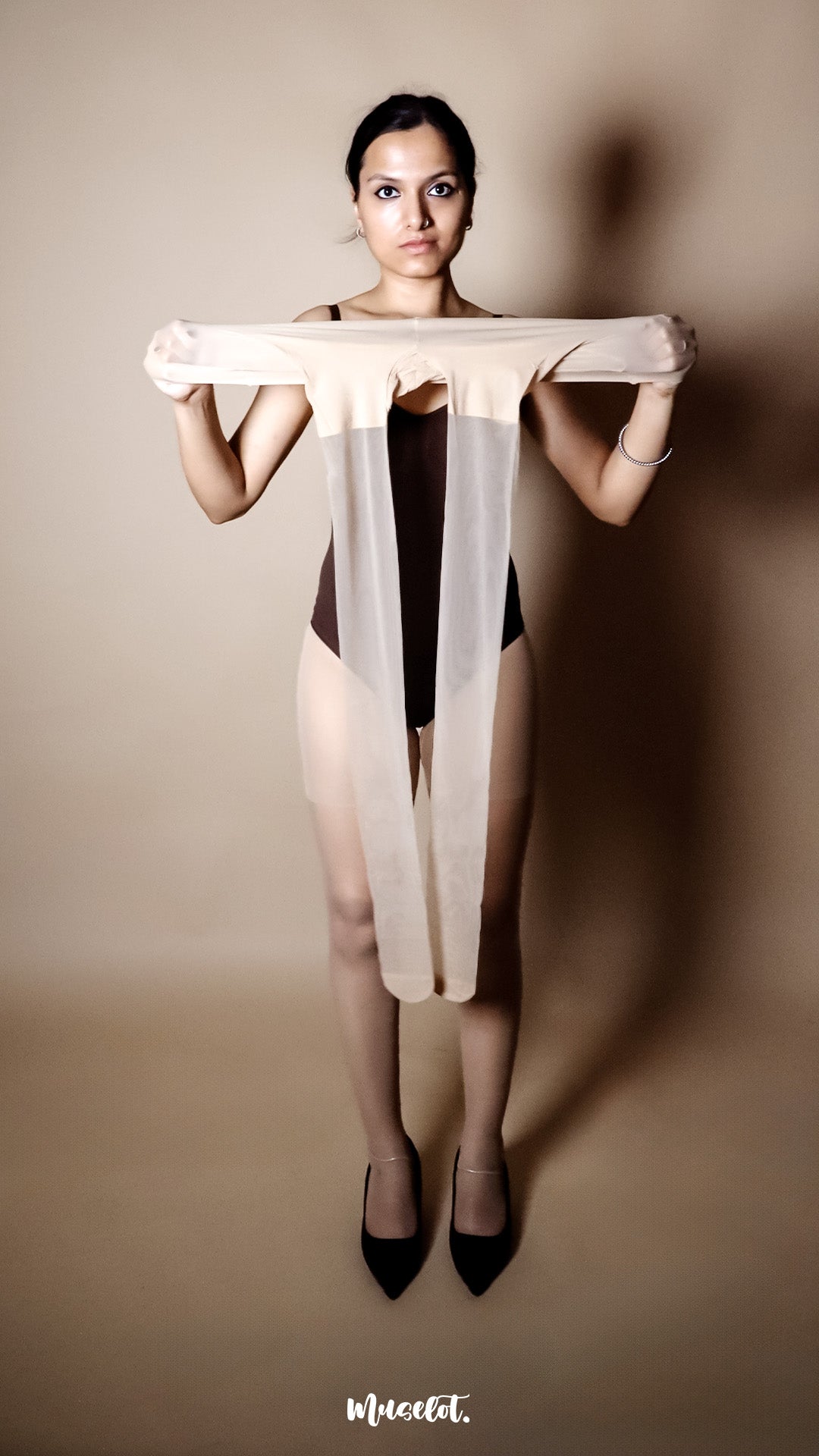 A woman holding nude pantyhose in hands, ultra thin stockings for women showcasing full product length and transparency - Muselot