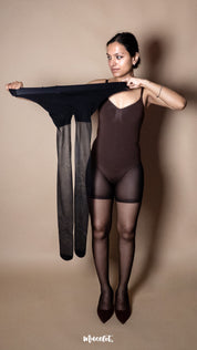 A model wearing black sheer pantyhose styled with a bodysuit, front pose holding the stockings on a beige background highlighting stretchability and product detail — Muselot